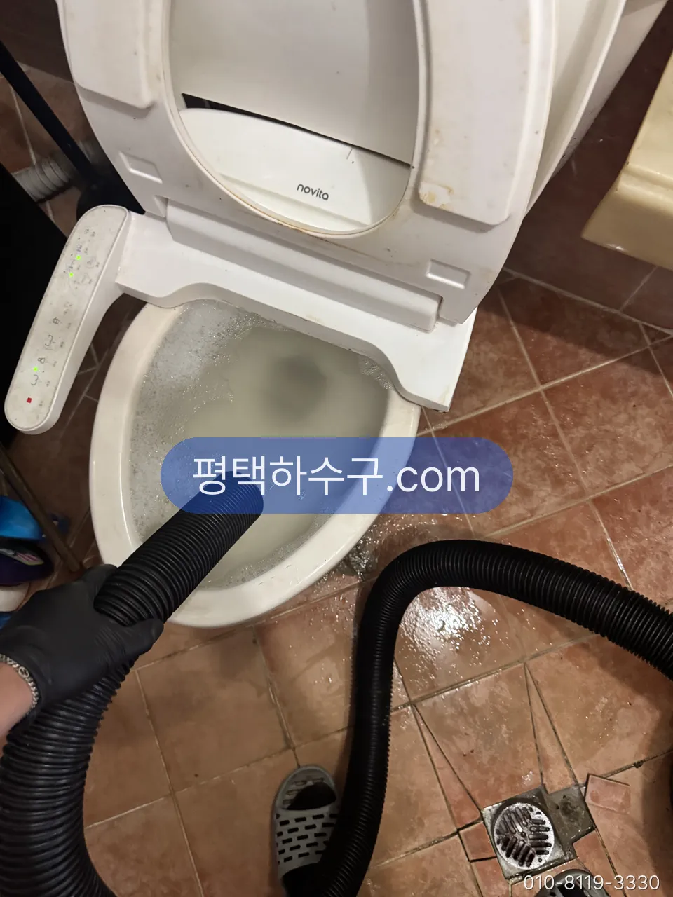 석션 호스를 변기에 넣어 물과 이물을 빨아내는 중